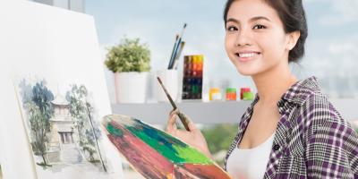Student artist smiling with paint brush and paint palette